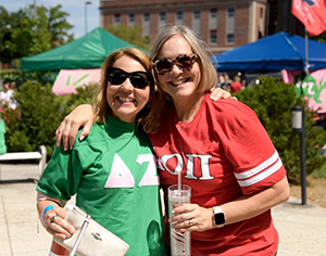 photo of two women hugging wearing shirts with Greek emblems