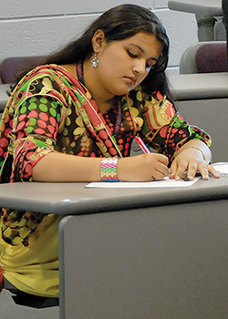 female international student bent over a desk and writing