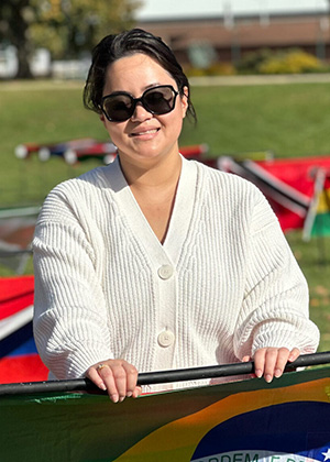 a current female Ship student standing next to her country's flag